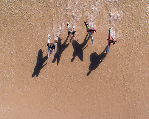 Surfers running into water